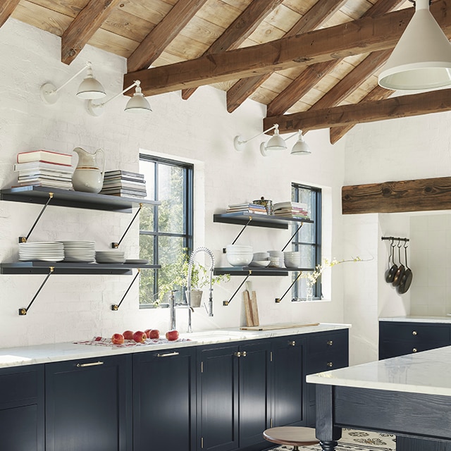 Grande cuisine à aire ouverte avec murs blancs, plafond voûté en bois et magnifiques armoires enduites d’un spectaculaire bleu foncé. Grande cuisine à aire ouverte avec murs blancs, plafond voûté en bois et magnifiques armoires enduites d’un spectaculaire bleu foncé.