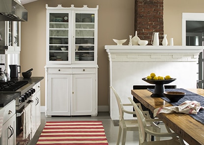 Une cuisine aux murs brun clair présentant un bahut blanc, un foyer blanc et un tapis de passage rayé rouge et blanc. Une cuisine aux murs brun clair présentant un bahut blanc, un foyer blanc et un tapis de passage rayé rouge et blanc.