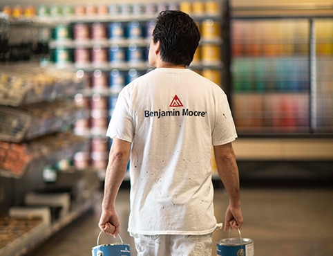 A painting contractor carries cans of premium paint through a Benjamin Moore® independent retailer. A painting contractor carries cans of premium paint through a Benjamin Moore® independent retailer.